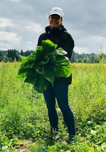 Angela holding leafy produce on a small farm