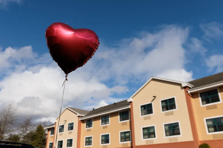 A heart-shaped balloon held outside an apartment building